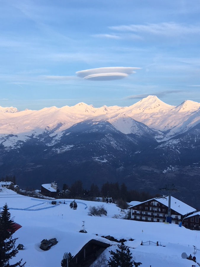 a lenticular ufo- like formation hovers over
